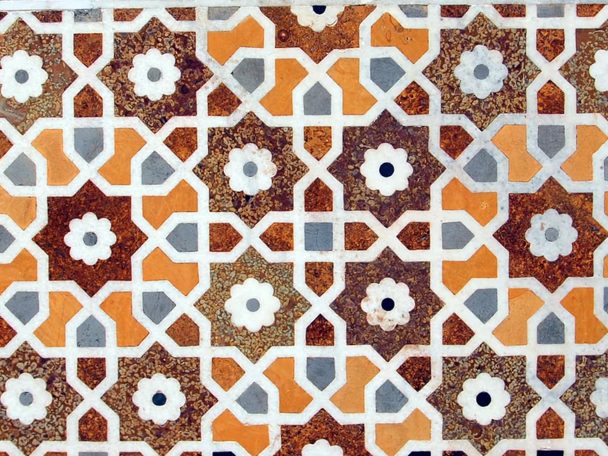 Inlaid stone on a turret of the tomb of I'timad-ud-Daulah in Agra: eight-pointed stars in browns and ochre, joined by white marble lines.