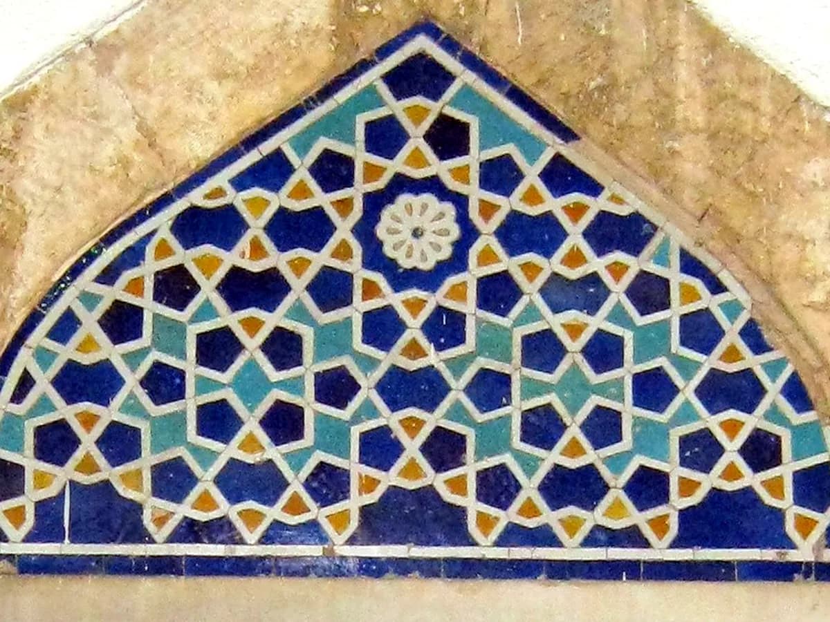 The tile tympanum over a window of the Muradiye Mosque in Bursa: ten-pointed stars in deep blue, turquoise and gold, joined by white lines, a small flower at the top.