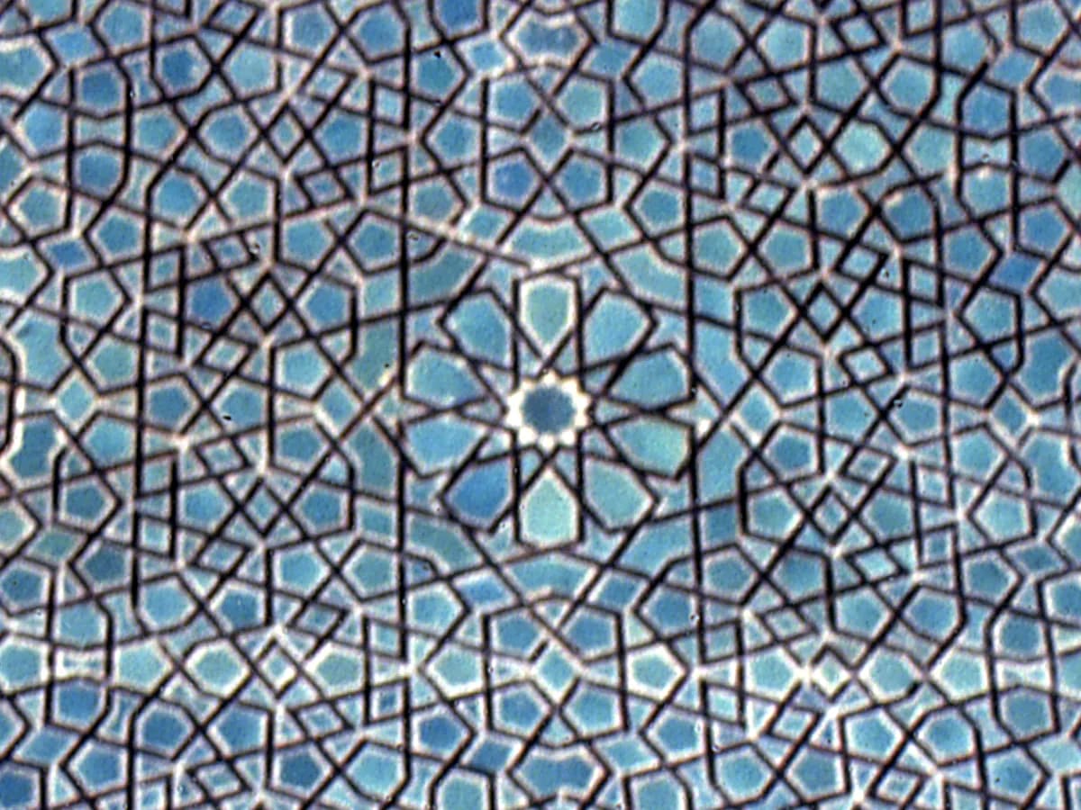 A tiled vault panel in the Karatay Madrasa, Konya: interlacing lines in turquoise and dark blue around a ten-fold rosette.